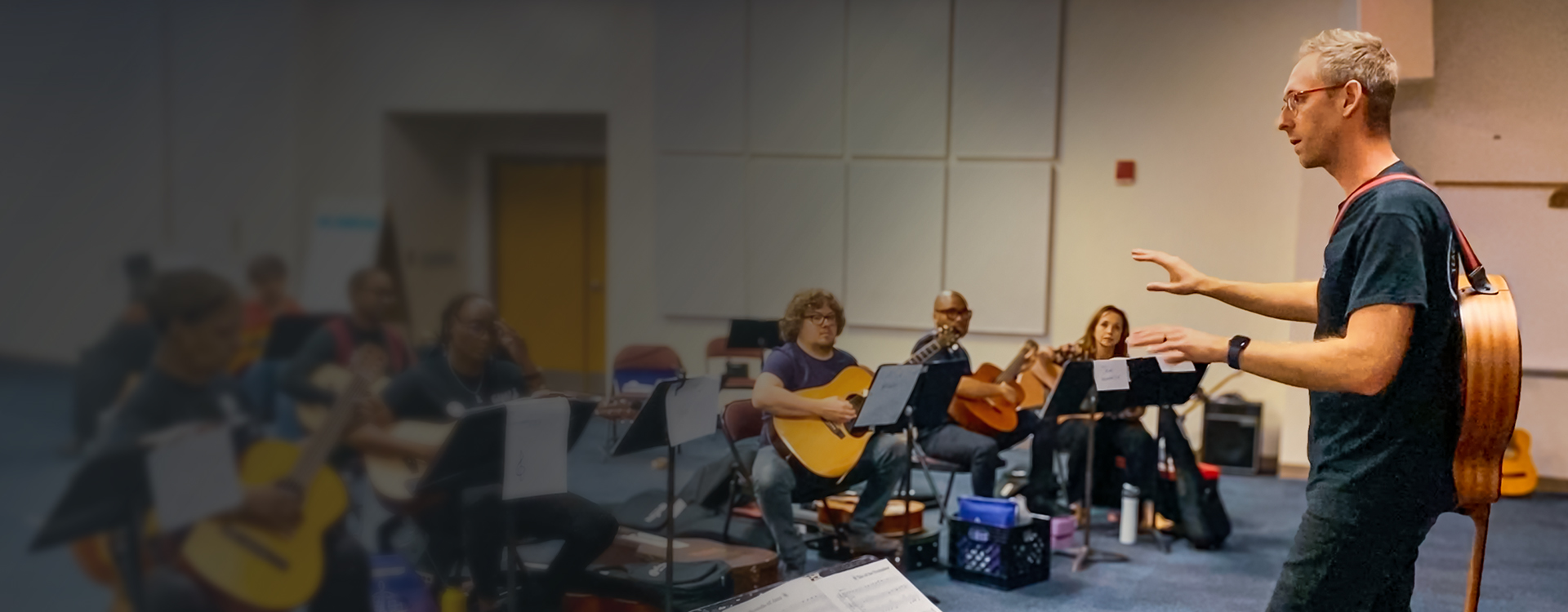 Instructor leading a Teaching Guitar Workshops class with adult students playing guitars