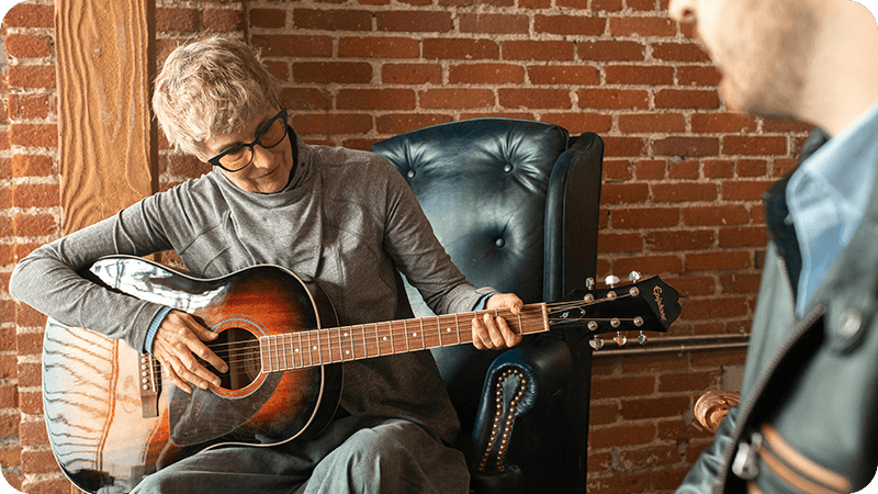 Adult student practicing acoustic guitar during a one-on-one lesson