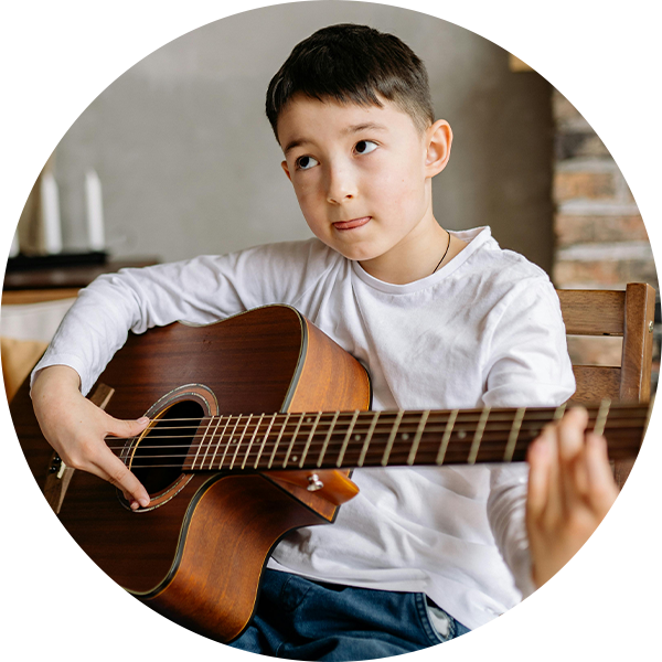 Young boy learning beginner guitar chords on an acoustic guitar