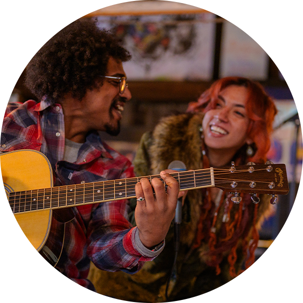 Two musicians smiling and performing together with an acoustic guitar