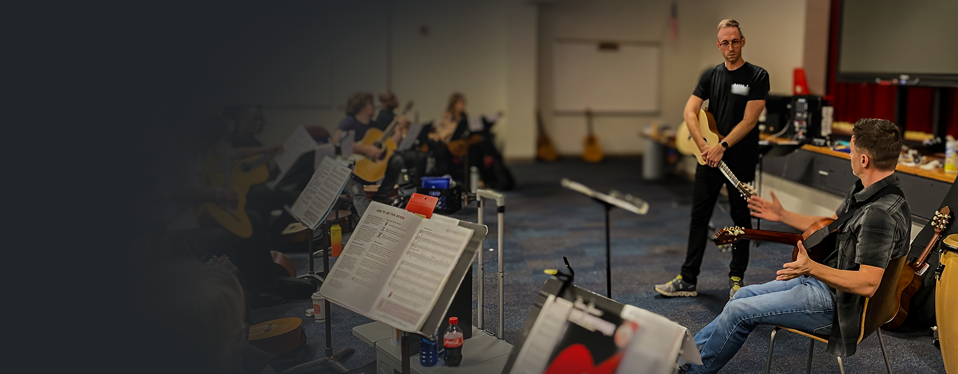 Guitar workshop class with an instructor teaching while students practice