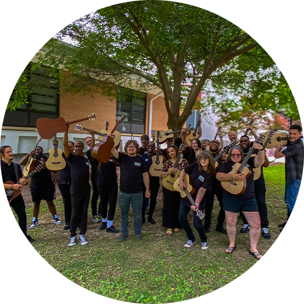 Group of smiling music educators holding guitars and celebrating outdoors