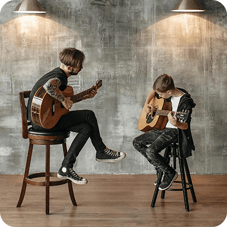Guitar teacher and student practicing together in a modern studio space.