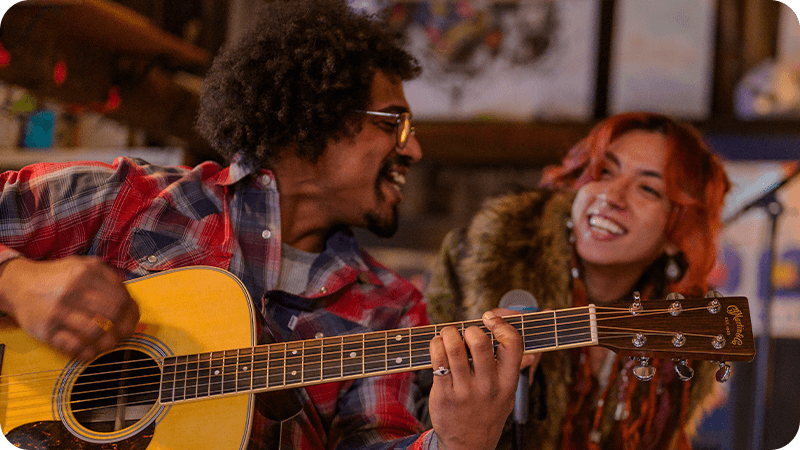 Guitarist and singer performing together in a relaxed studio setting.