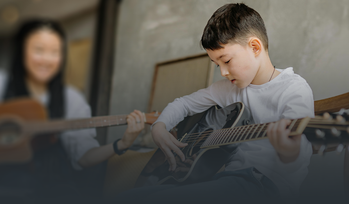 young boy playing acoustic guitar
