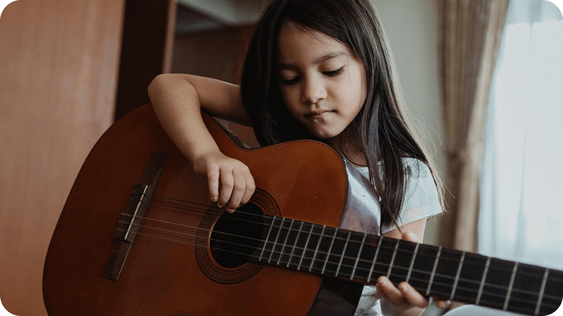 Young student learning to play guitar indoors
